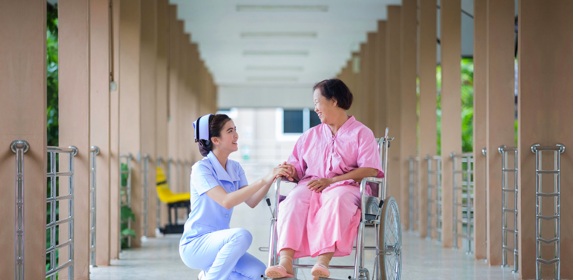 caregiver holding the hand of senior woman on wheelchair