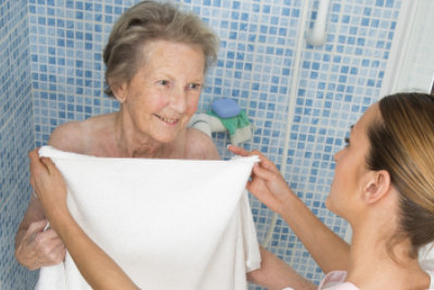female caregiver assisting senior woman after taking a shower