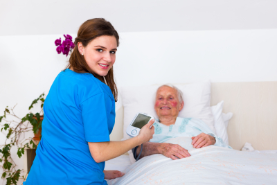 female nurse taking care and measuring blood pressure of senior woman